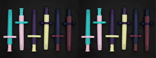 A collection of 12 multi colored Sniff & Slide spring loaded bump straw pendants, From the Color Remix Collection, arranged in a line.