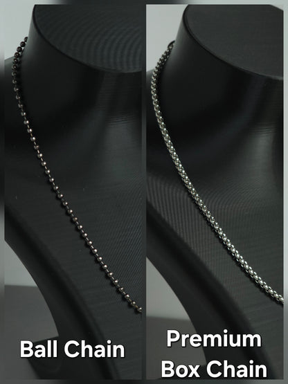 A split comparison of two necklace chains displayed on a black mannequin bust. The left side shows a dark metallic ball chain labeled 'Ball Chain', and the right side shows a silver-toned premium box chain labeled 'Premium Box Chain'.
