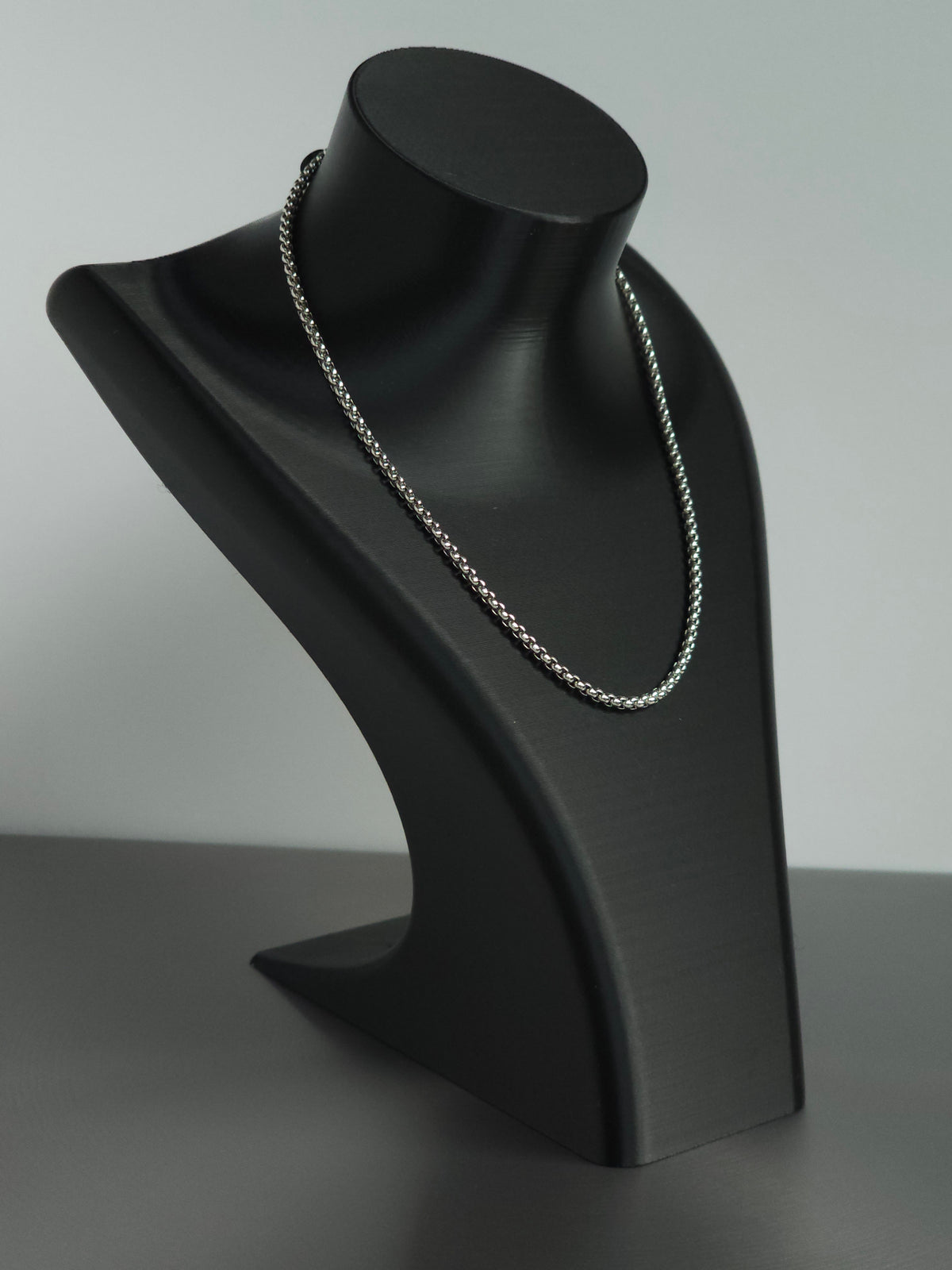 A silver-toned chain necklace displayed on a matte black jewelry bust against a light gray background. An upgrade to the stock Sniff and Slide spice straw necklace