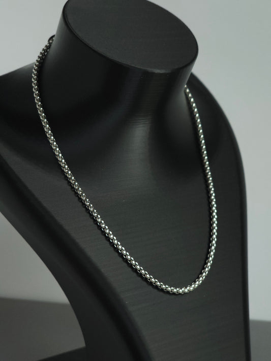A zoomed in view of a silver-toned chain necklace displayed on a matte black jewelry bust against a light gray background. An upgrade to the stock Sniff and Slide spice straw necklace