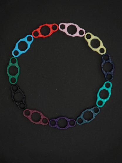 A circular arrangement of colorful, color remix necklace adapters on a dark gray background.