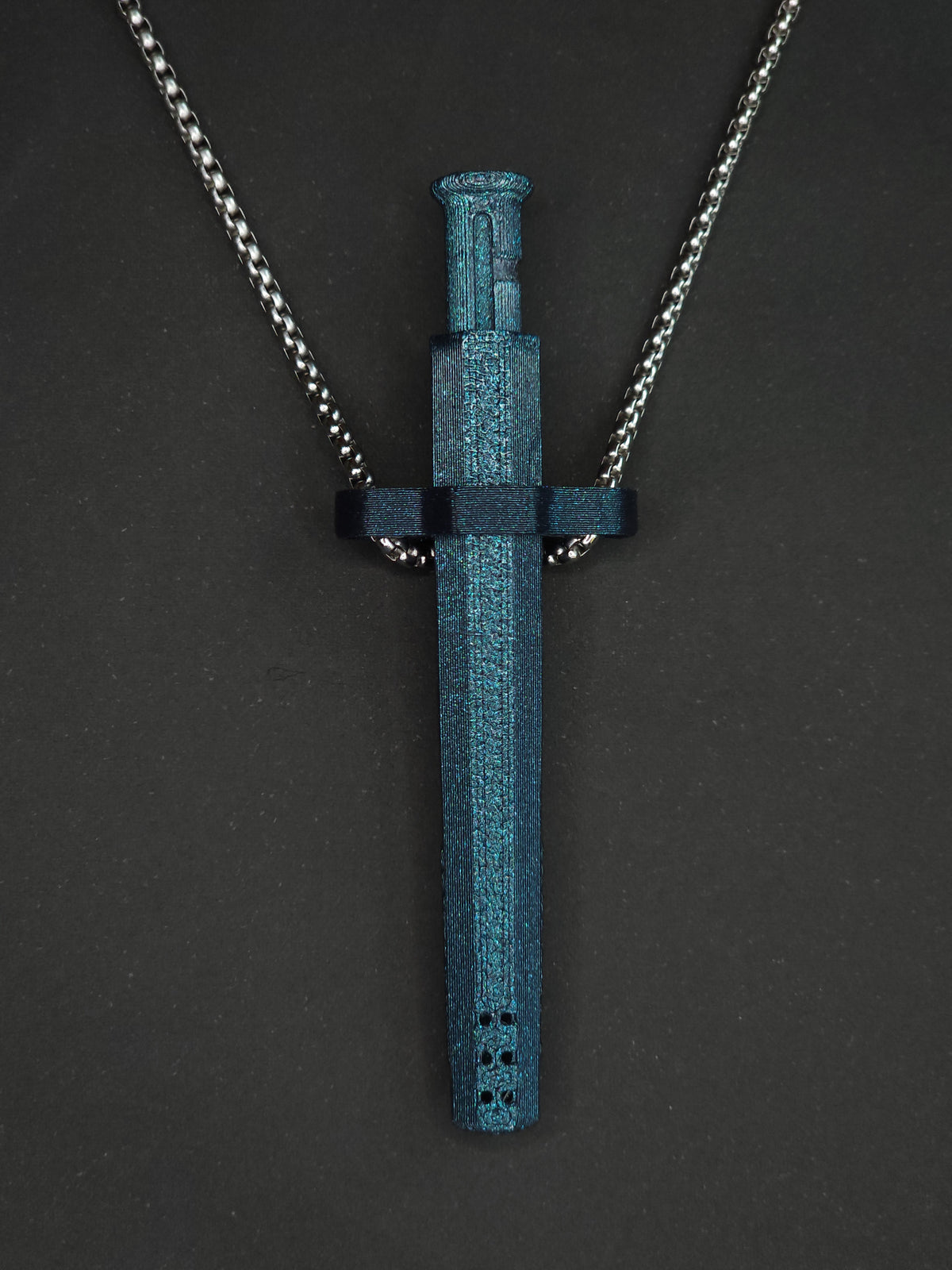 A galaxy blue spring-loaded bump straw pendant on a silver box chain, displayed against a dark textured background