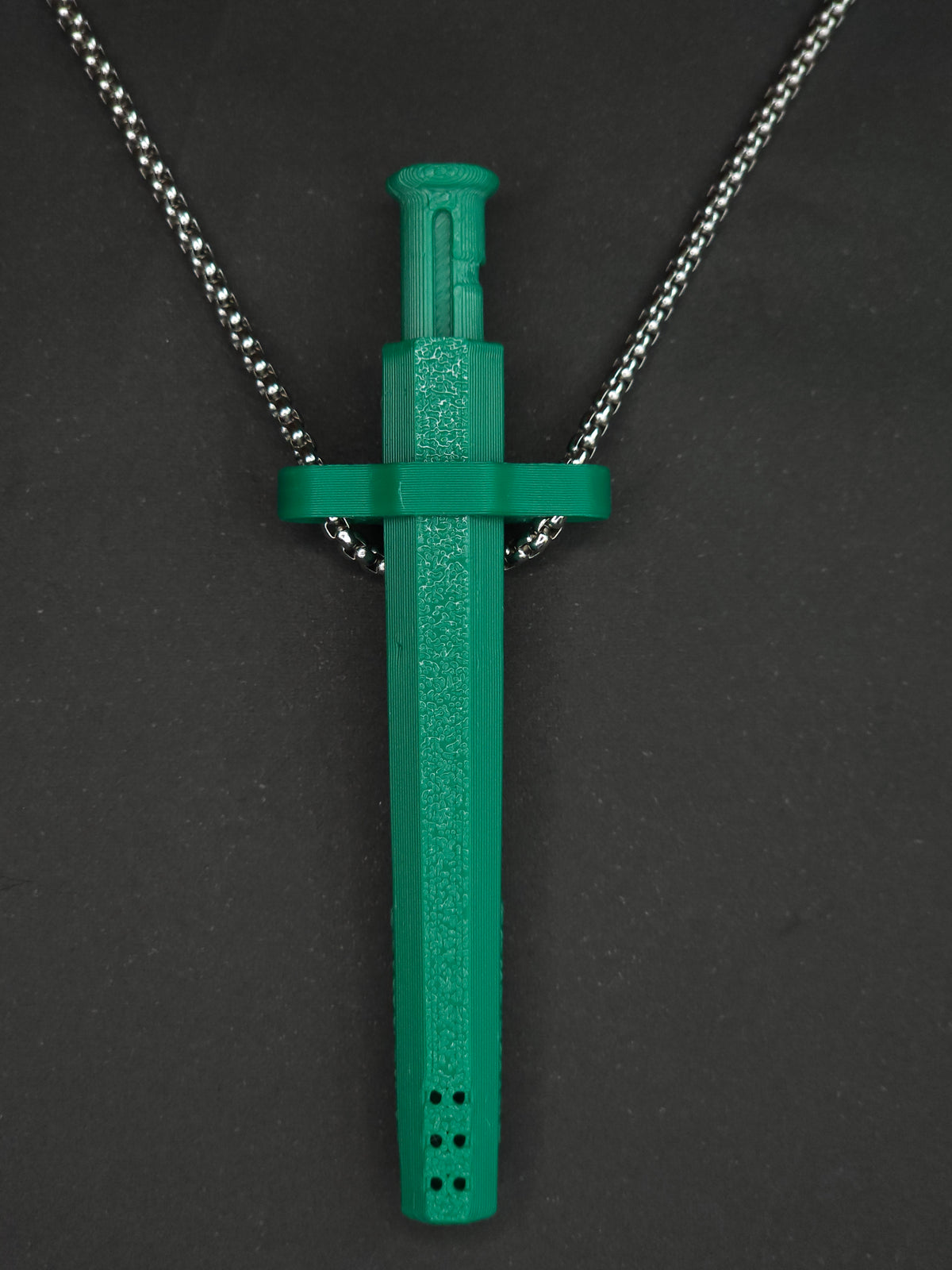 A green spring-loaded bump straw pendant on a silver box chain, displayed against a dark textured background