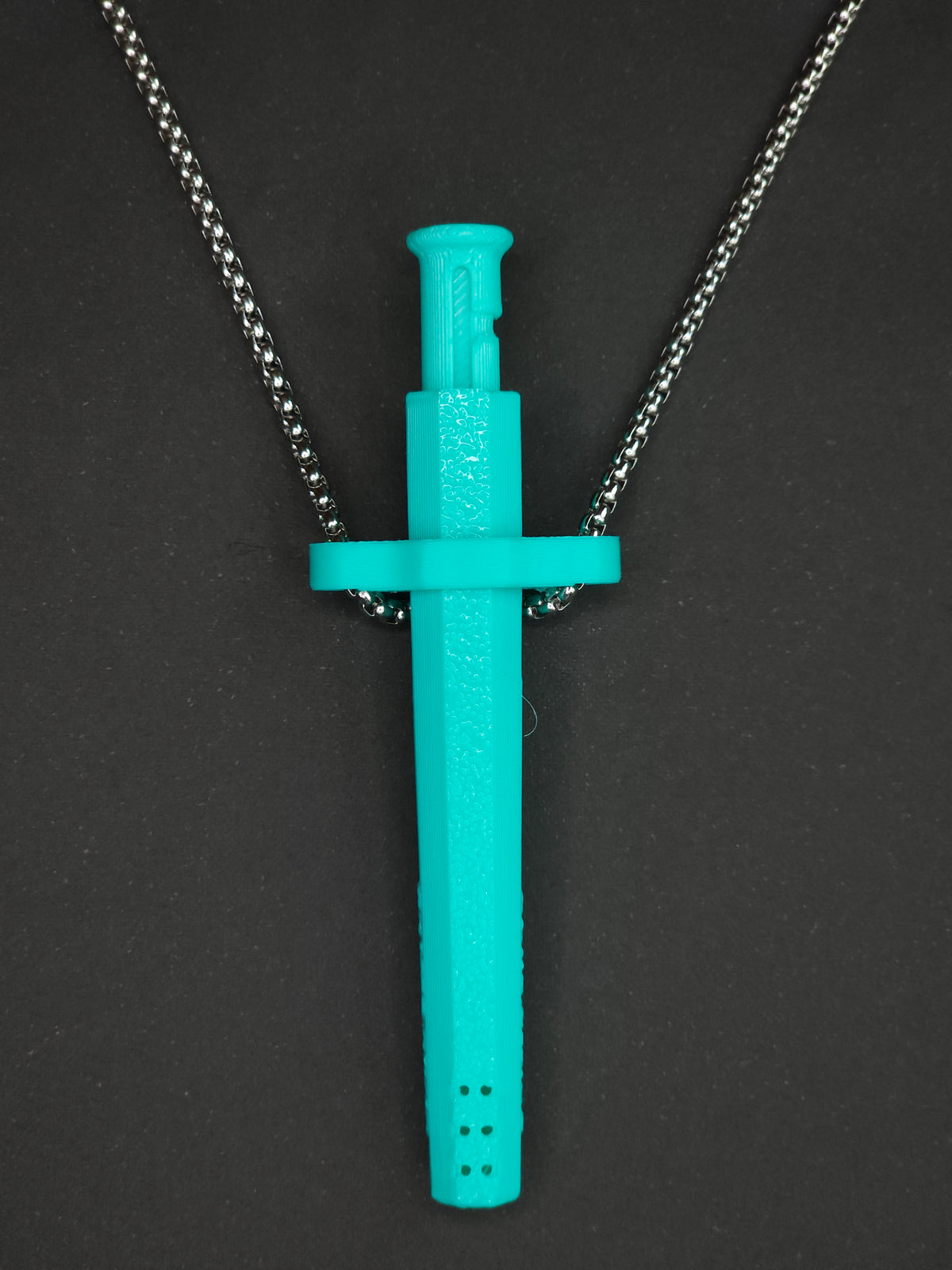 A mint green spring-loaded bump straw pendant on a silver box chain, displayed against a dark textured background