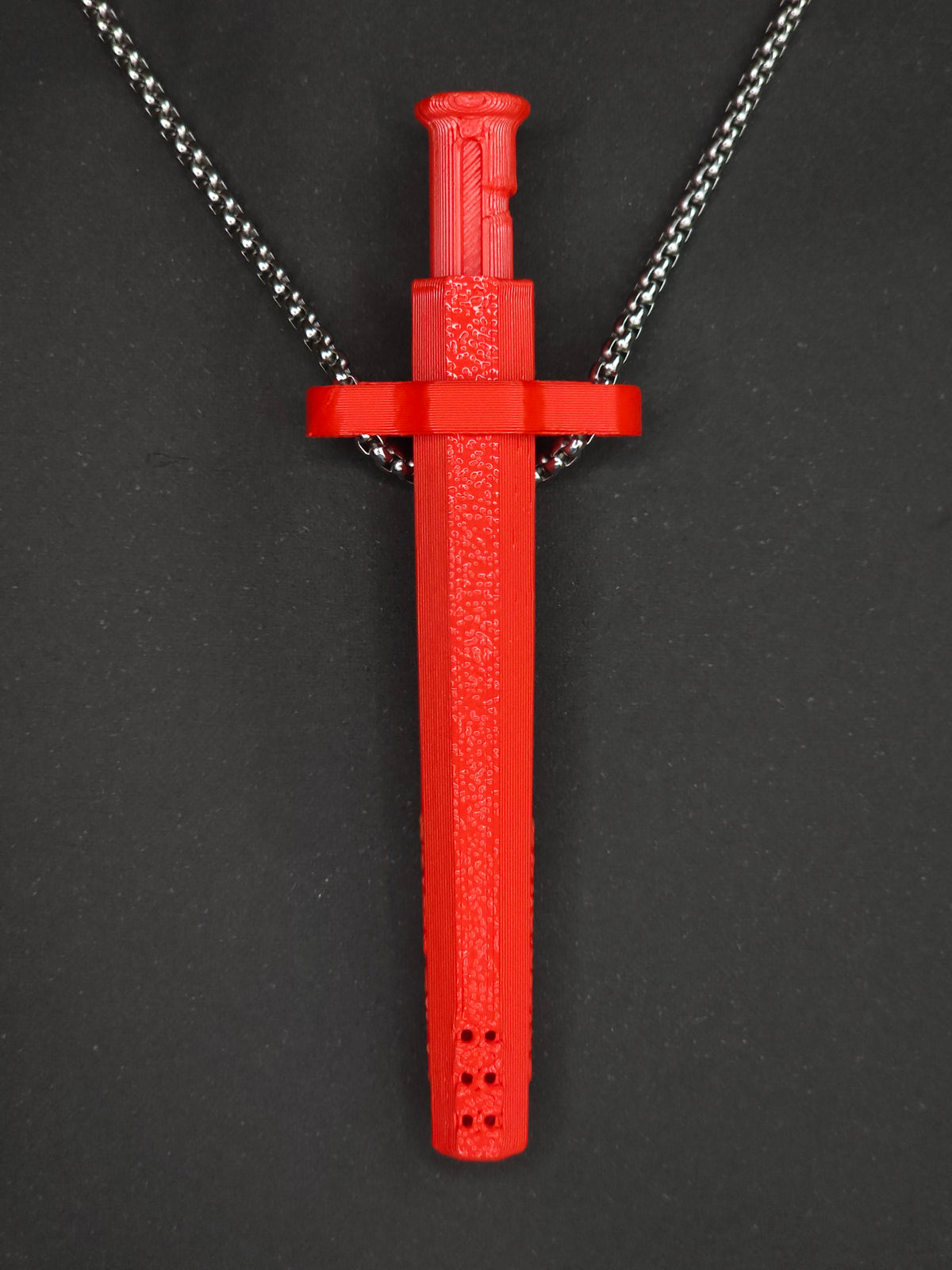 A red spring-loaded bump straw pendant on a silver box chain, displayed against a dark textured background