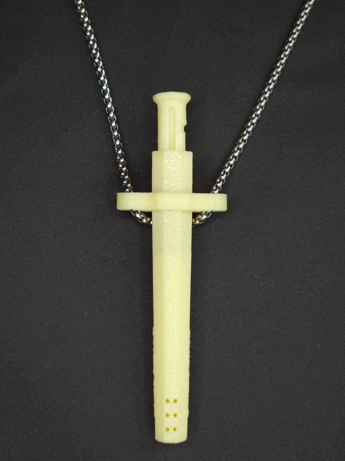 A yellow spring-loaded bump straw pendant on a silver box chain, displayed against a dark textured background