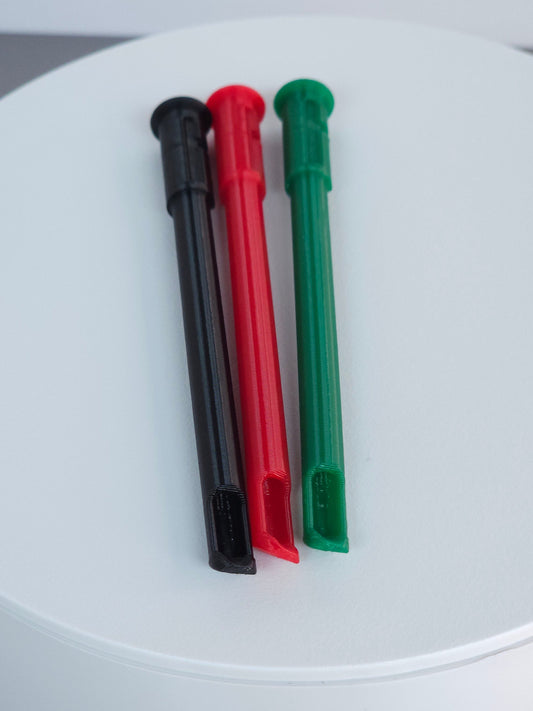 Three plastic straw and scoop inserts, red, black and green, arranged vertically on a round white display pedestal.