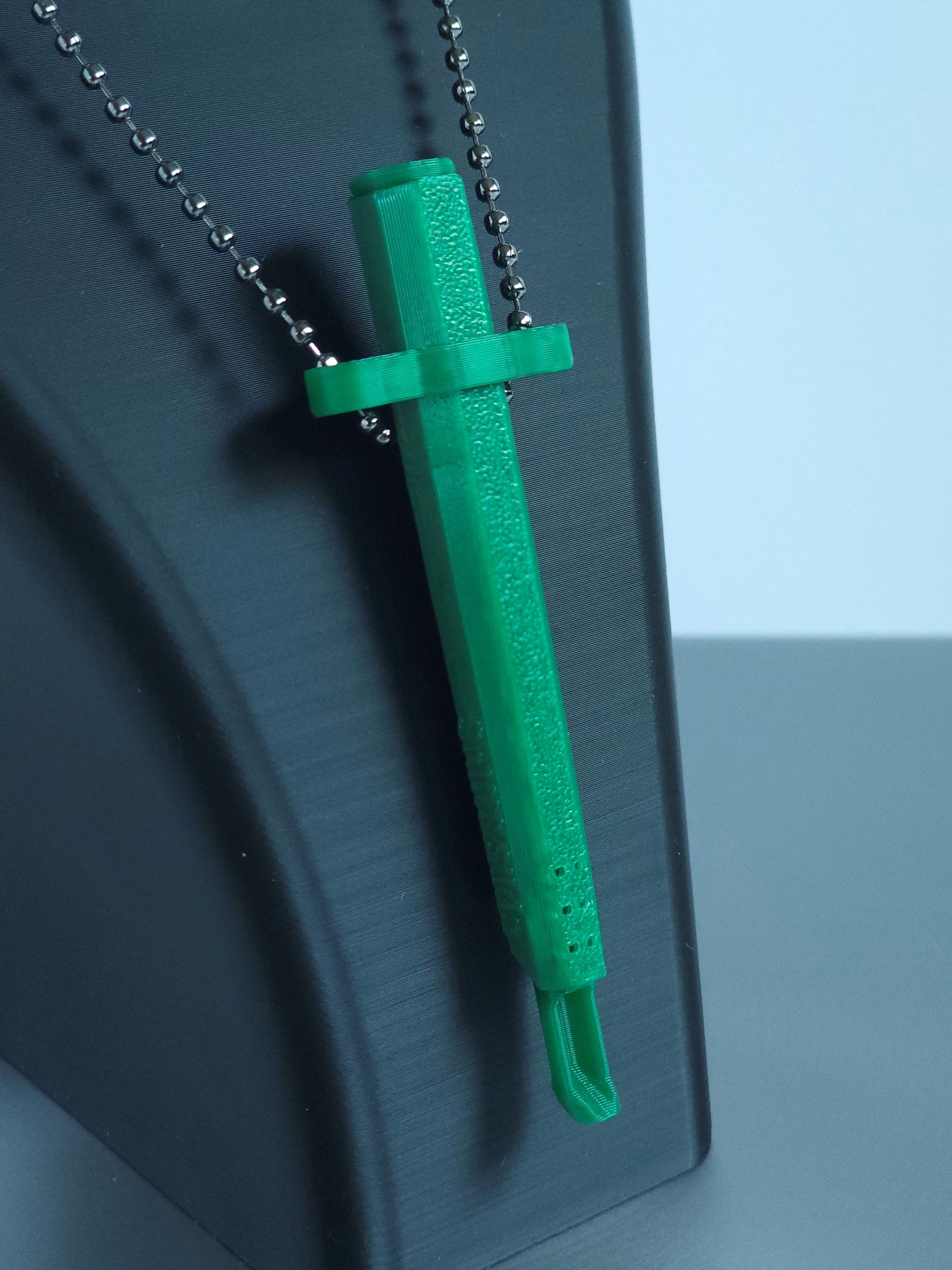 Sniff & Slide spring-loaded bump straw in emerald Green with silver ball chain, displayed on black mannequin bust, over a white and grey background. The insert is extended, showing the straw scoop extending from it's end.