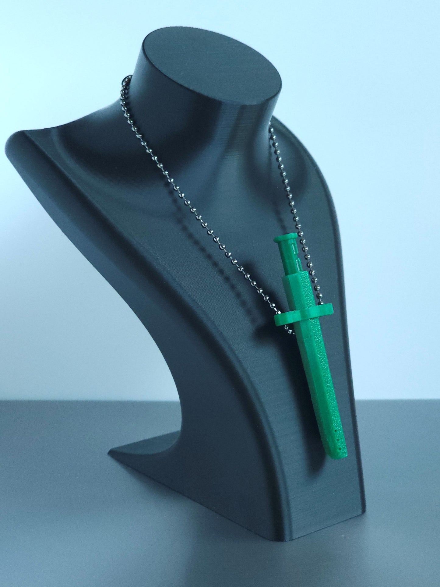 Sniff & Slide spring-loaded dispenser pendant in emerald Green with silver ball chain, displayed on black mannequin bust, over a white and grey background