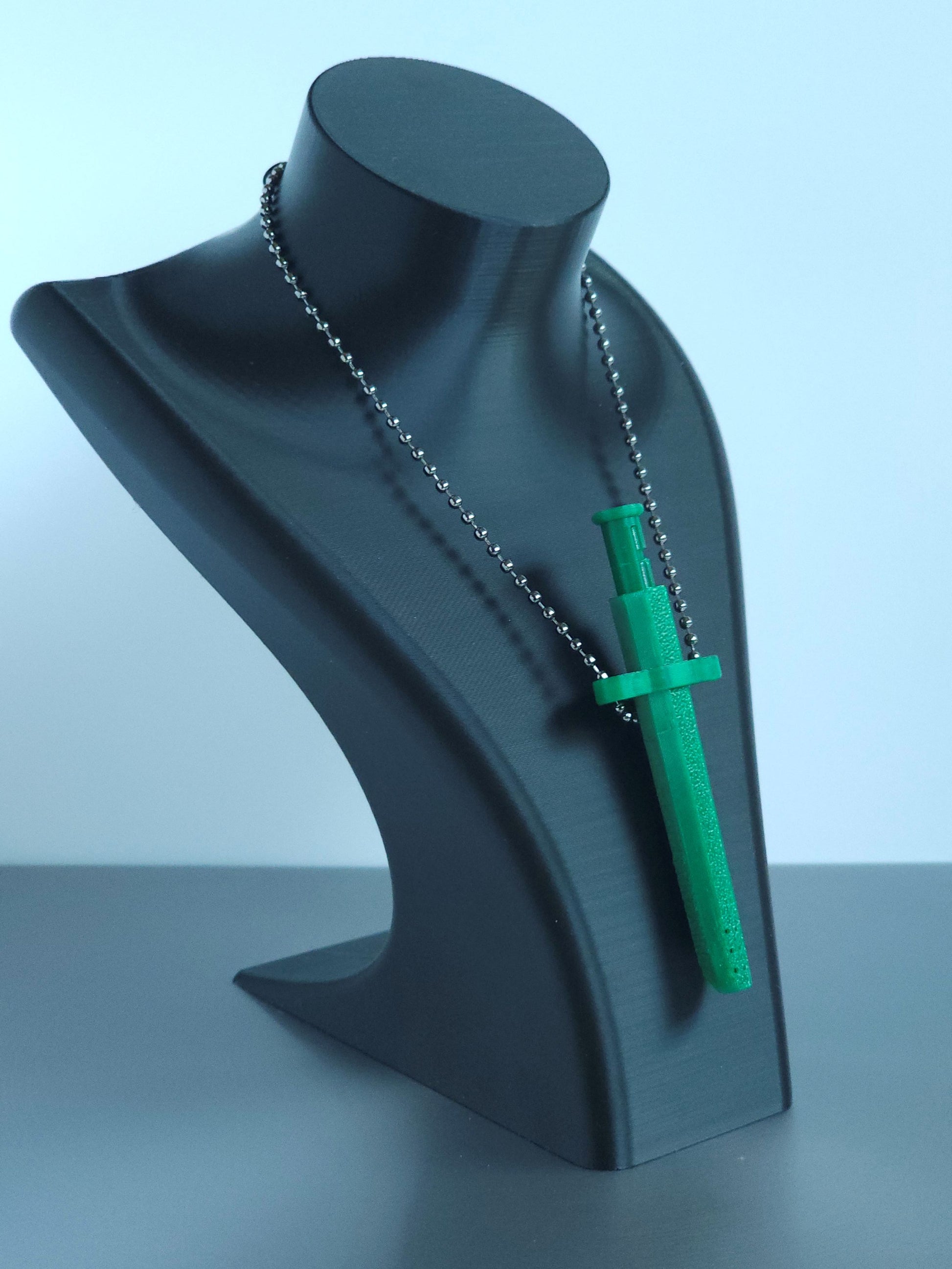 Sniff & Slide spring-loaded dispenser pendant in emerald Green with silver ball chain, displayed on black mannequin bust, over a white and grey background